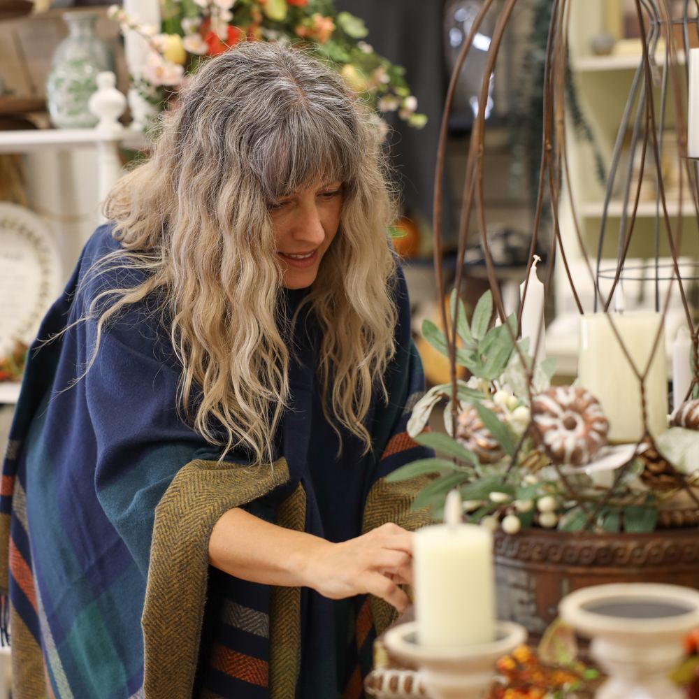 Ellen setting a pillar candle into its holder on a display table