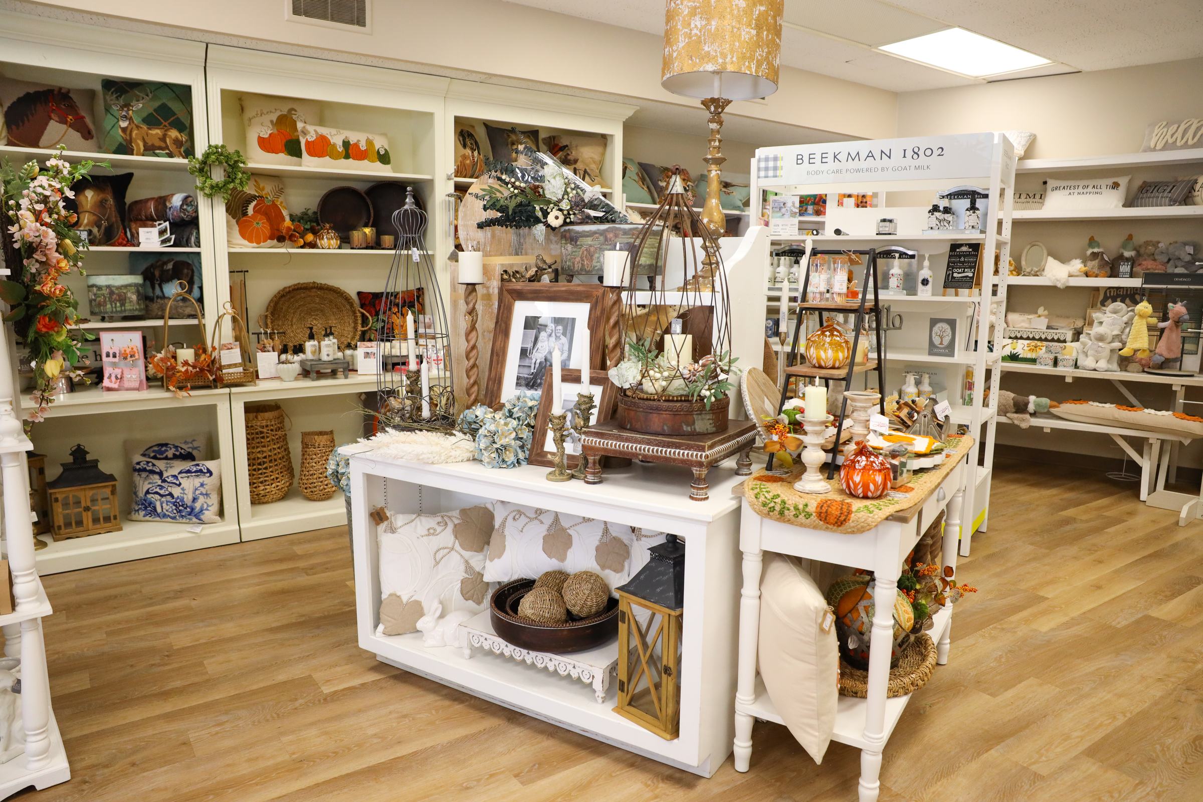 Inside The Finishing Touch Store: a display table of lanterns, candles, and seasonal accents in front of the Beekman 1802 shelves